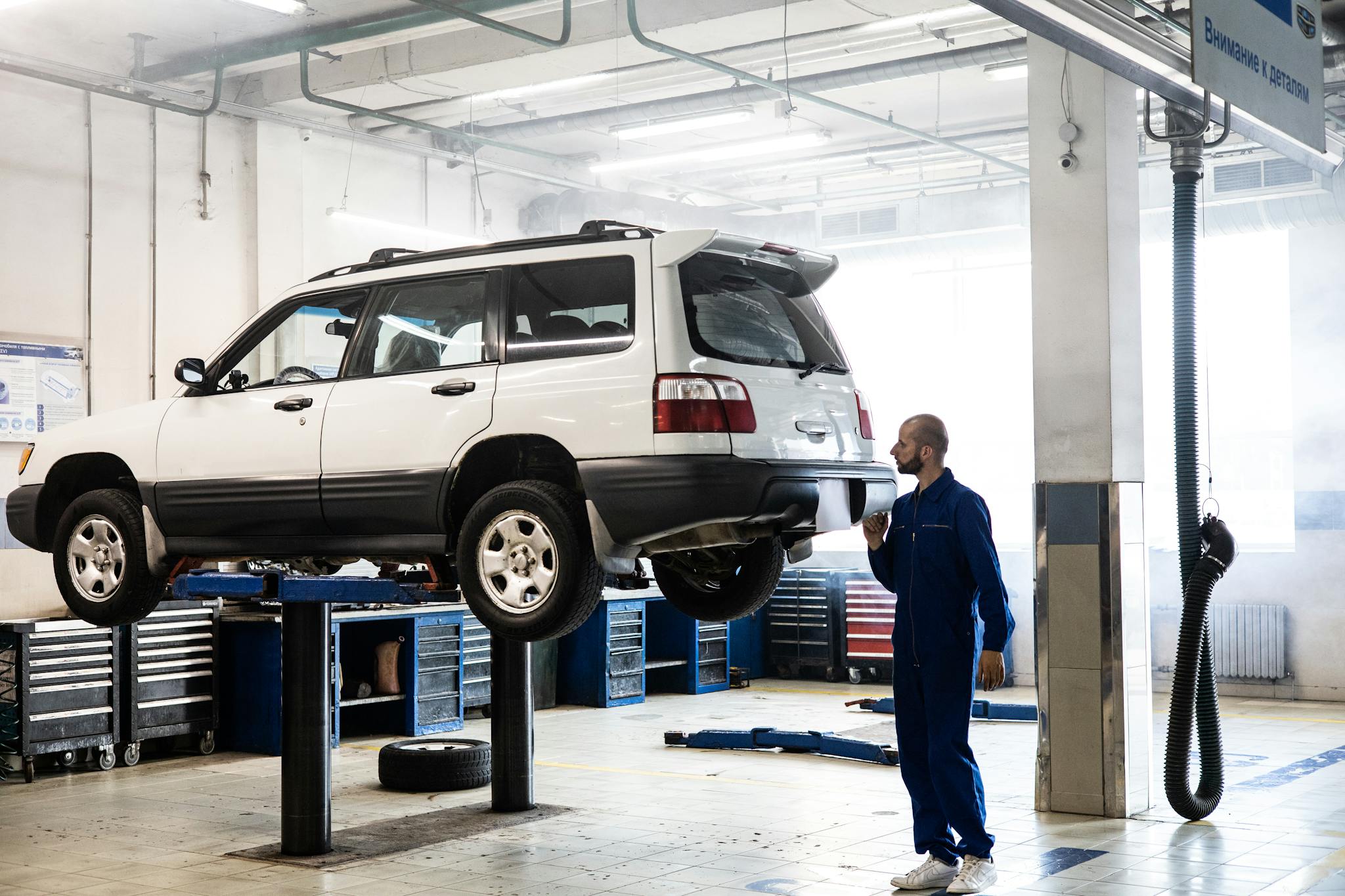 Mechanic inspecting a lifted SUV in a modern auto repair garage.
